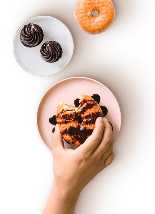 A hand taking a donut from a plate with two more donuts, some scattered blueberries, and a bowl of crumbs on the TechRyde website a Restaurant Software Service provider.