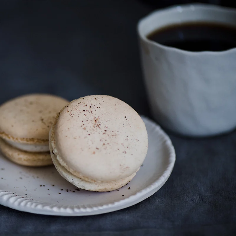 Macarons on a plate next to a cup of coffee. Restaurant technology and management software helping enhance the dining experience from TechRyde present on website.