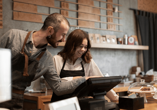 Scale Without Changing Systems Coffee shop workers using a POS system at the counter.<br />