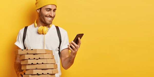 Man holding pizza boxes and looking at a smartphone