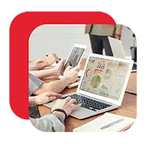 People analyzing business reports on a laptop at a table.<br />